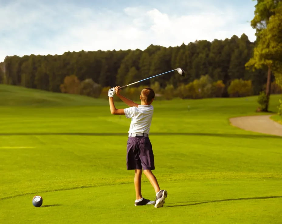 a boy swinging a golf club