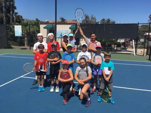 a group of kids posing for a photo on a tennis court