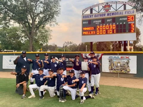 a group of people posing for a photo in front of a scoreboard