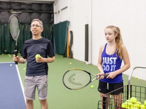 a couple of people stand near each other holding tennis rackets