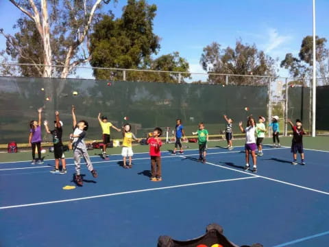 a group of kids playing tennis