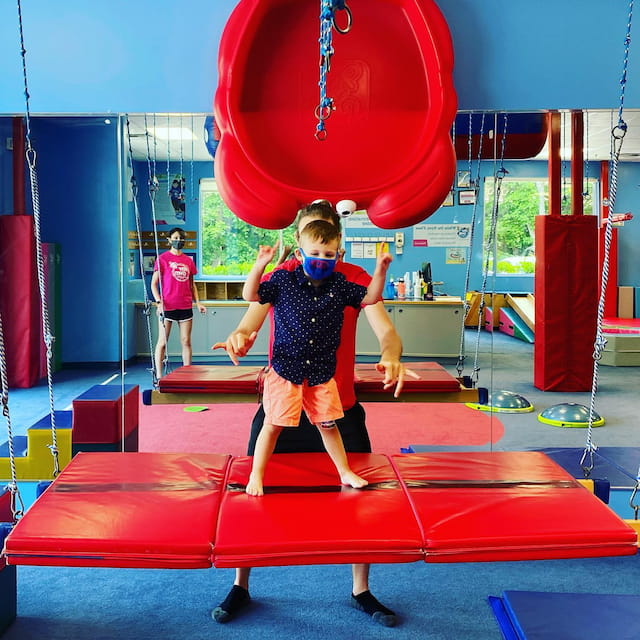 a boy standing on a red and blue slide