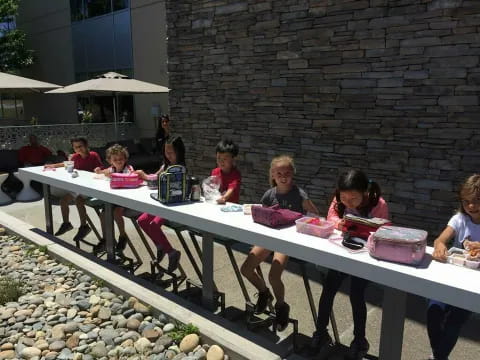 a group of kids sitting at a table outside