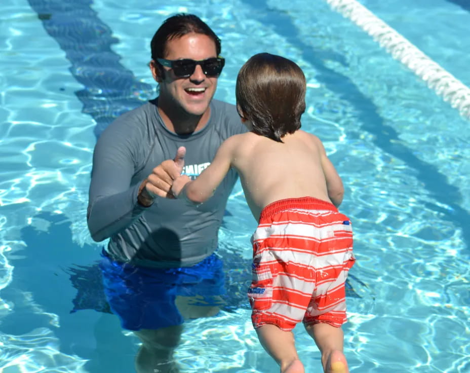 a person holding a baby in a pool