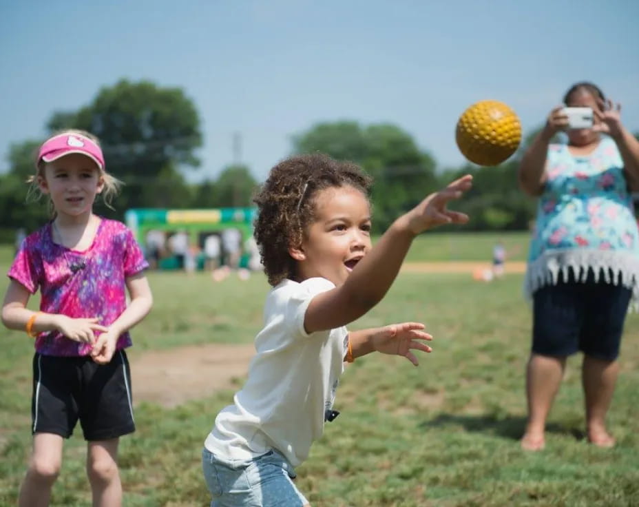 a group of children playing with a ball in a field