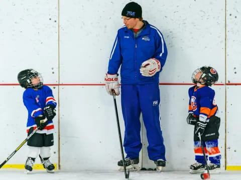 a man and a couple kids playing hockey