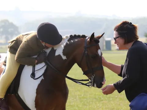 a woman and a man petting a horse