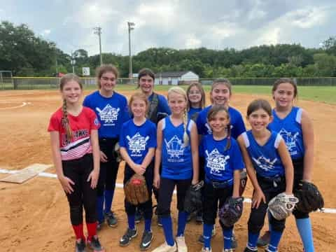 a group of girls wearing softball uniforms