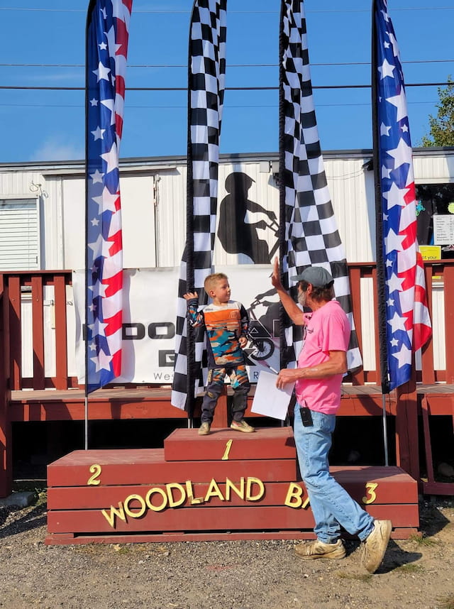 a person and a boy standing next to a sign with flags