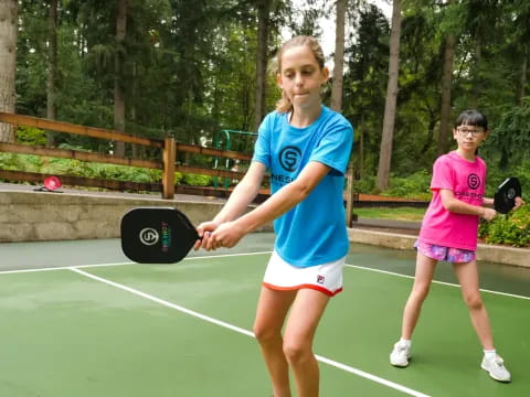 a couple of girls holding tennis rackets on a tennis court