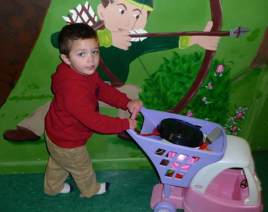 a boy standing next to a toy car