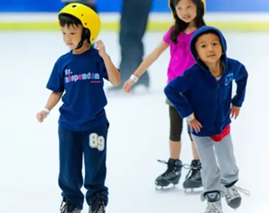 a group of kids wearing ice skates and helmets