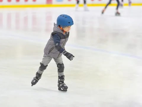 a child wearing a helmet and ice skates on ice