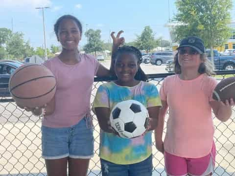 a group of girls holding football balls