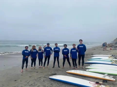 a group of people standing on a beach with surfboards