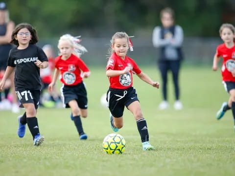 a group of young girls compete over a football ball