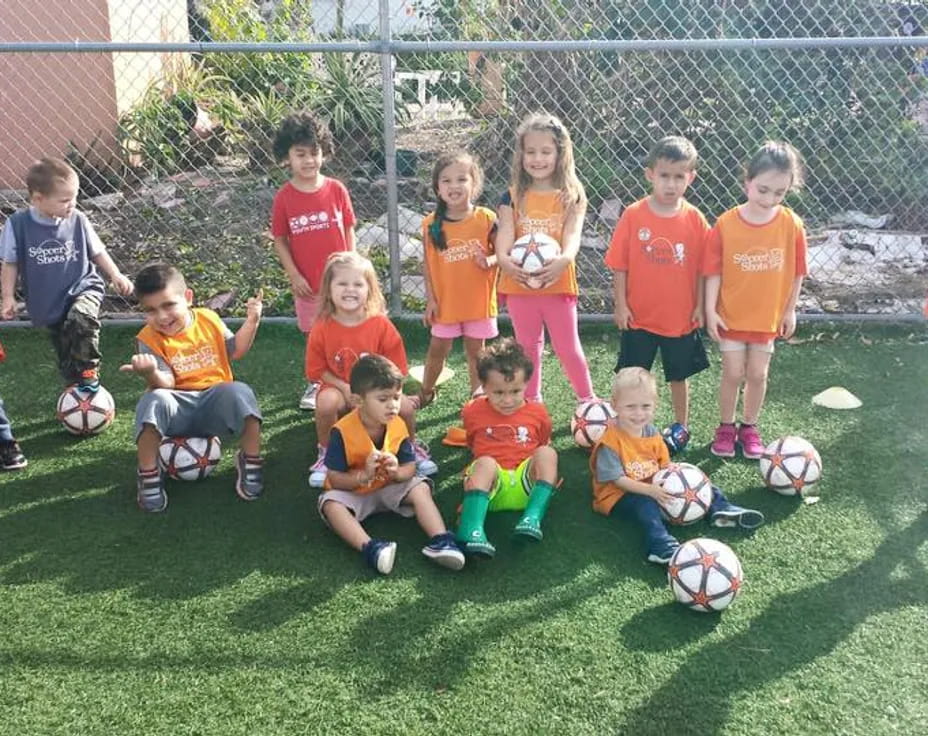 a group of kids posing for a picture with football balls