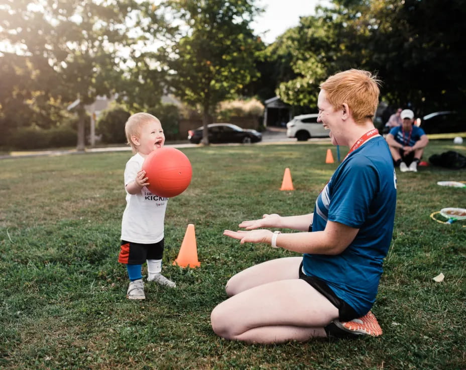 a person and a child playing with a ball in a park