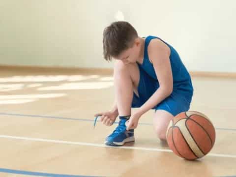 a boy kneeling on the floor with a basketball