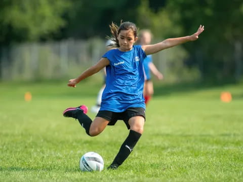 a girl kicking a football ball