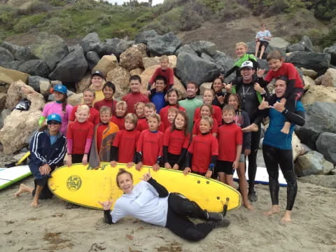 a group of people posing for a photo with a surfboard