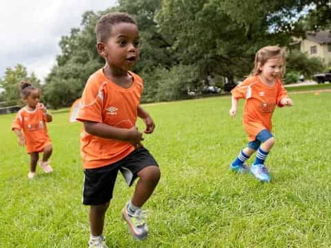 a group of children running on grass