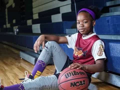 a girl sitting on the floor with a basketball