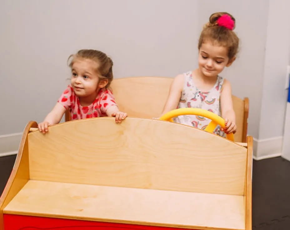 a couple of girls sitting on a couch with a box