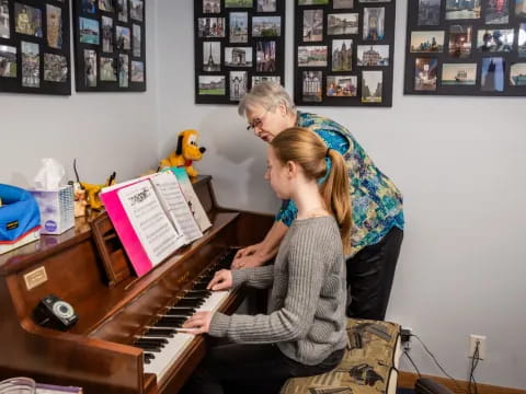 a woman playing a piano with a girl playing the piano