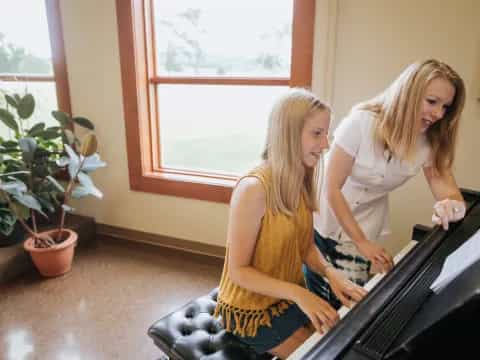 a couple of women sitting on a couch in front of a piano