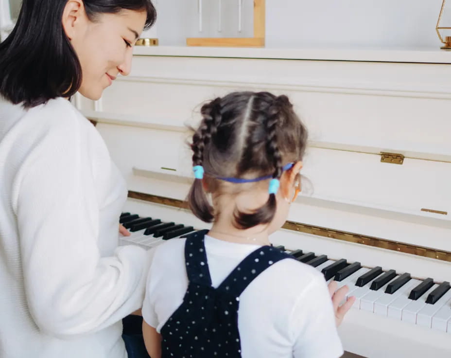 a woman playing a piano with a young girl