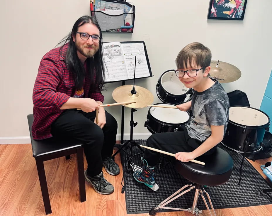 a person and a boy playing drums