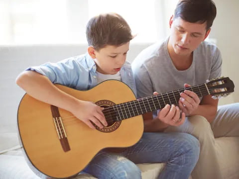 a person and a boy playing a guitar