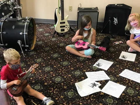 a group of children sitting on the floor with a guitar and a guitar