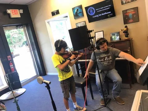 a person and a boy with bows and arrows in a room with posters