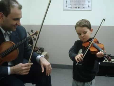 a man playing a violin next to a boy playing a violin
