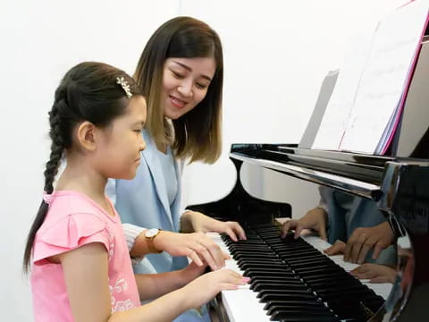 a woman and a girl playing piano
