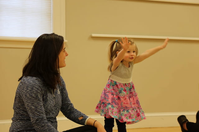 a woman holding a girl's hand in front of her