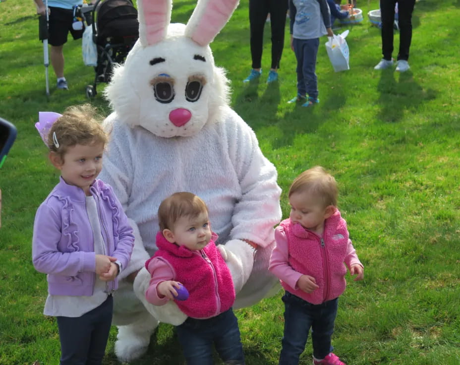 a group of children posing with a person in a rabbit garment