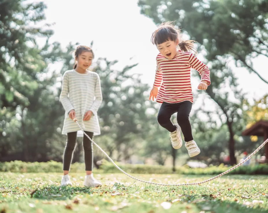 a couple of children running on a grass field
