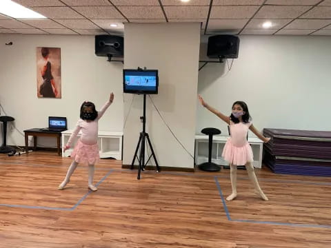 a couple of girls dancing in a room with a projector screen