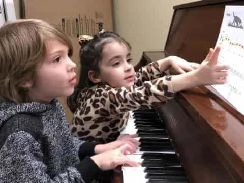 a couple of girls playing piano