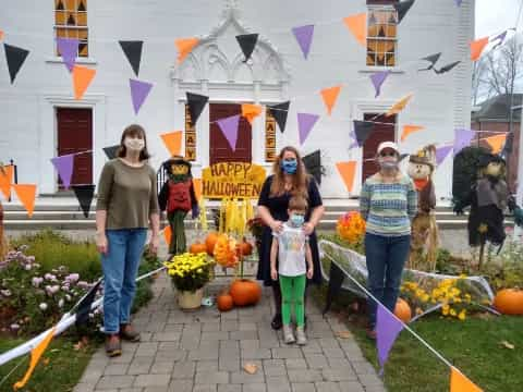 a group of people walking down a sidewalk with pumpkins and flowers