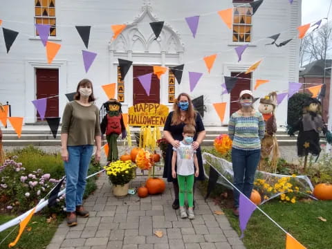 a group of people walking down a sidewalk with pumpkins and flowers