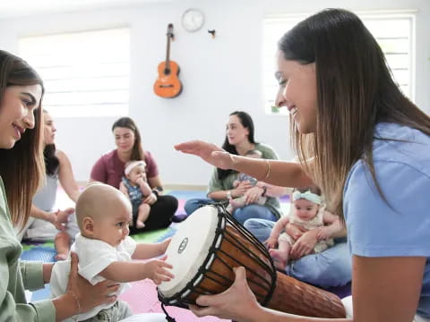 a group of people sitting in a room with a guitar and a woman holding a baby
