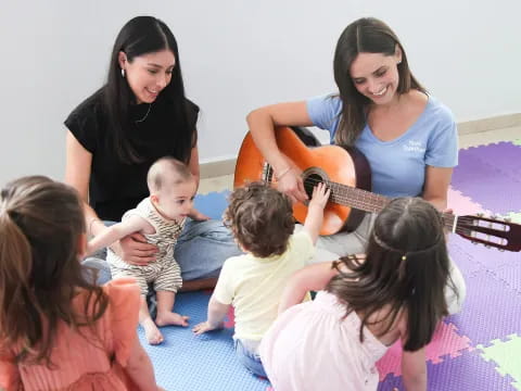 a woman playing guitar to a group of children