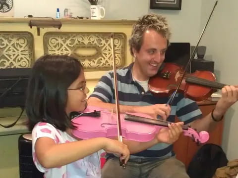 a person playing a violin with a young girl