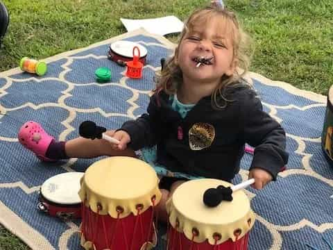 a girl sitting on a picnic table with a cake