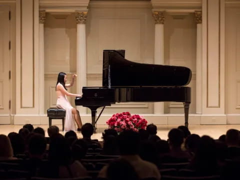 a person in a white dress playing a piano in front of a crowd