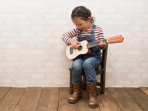 a girl sitting on a chair playing a guitar